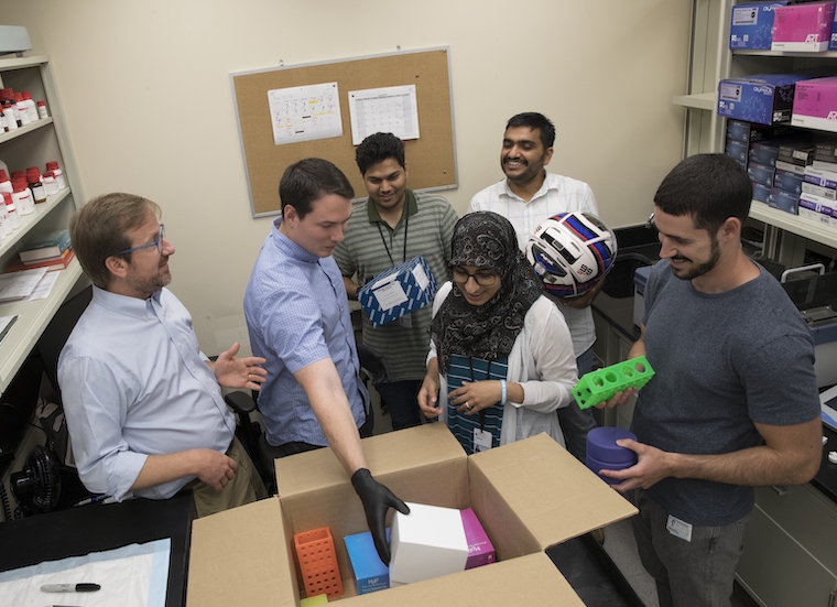 Members of Sean Moore's lab try to figure out how to best fit items in a box.